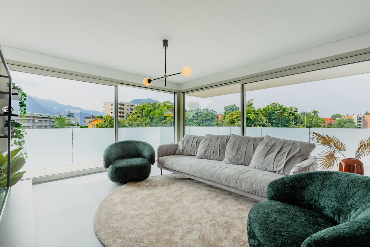 Spacious minimalist living room featuring large windows and stylish furniture with scenic views.
